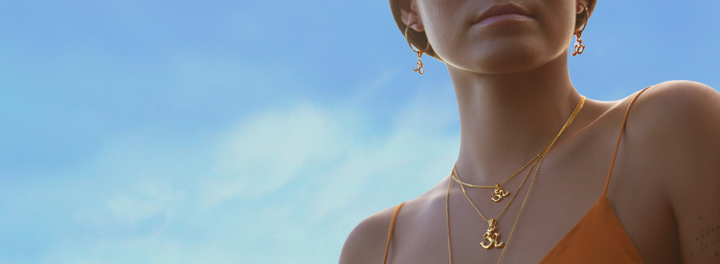 Steffi trägt zwei spirituelle Ketten aus der  Om Schmuck Kollektion und dazu passende Creolen mit Om Symbolen