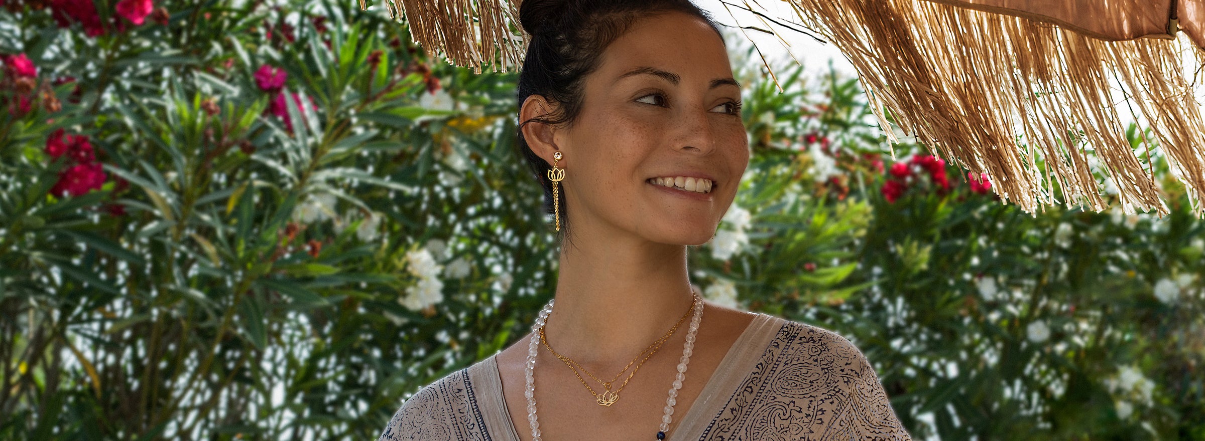 Spirituelle Schmuckkollektion: Steffi aus Bali trägt einen goldenen Lotus-Ohrring, Symbol der Geborgenheit mit einer Edelsteinkette