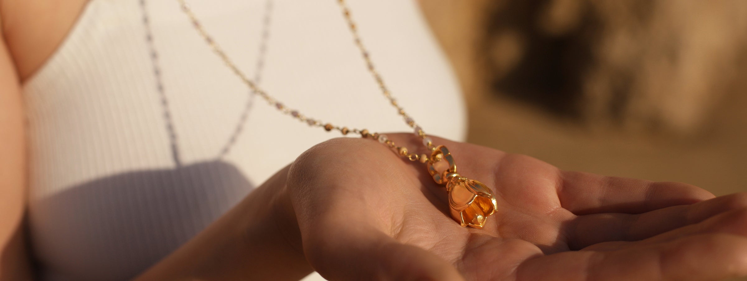 Spirituelle Schmuckkollektion: Gloria aus Berlin trägt einen goldenen Lotus-Glöckchen-Anhänger, Symbol der Geborgenheit an einer Edelsteinkette