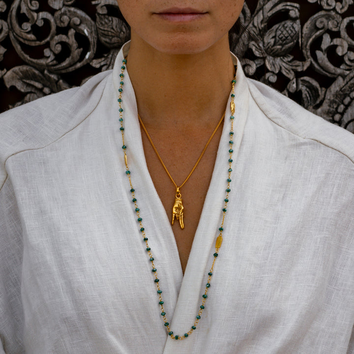 Yoga Teacher Steffi trägt eine Halskette aus hochwertig vergoldetem Sterling Silber mit Buddha-Emblemen und Jadeperlen 