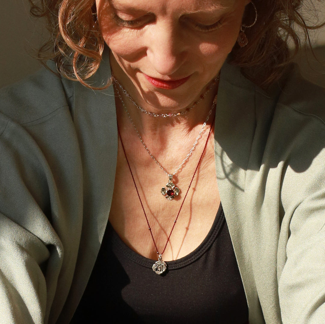 Elena Fröhlich, Yoga Lehrerin in Berlin, trägt den kleinen Wurzel-Chakra-Anhänger aus Sterling Silber an einer granatroten Halskordel