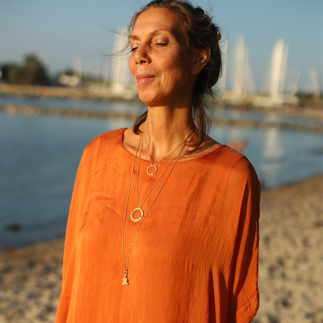 Die Berliner Unternehmerin Cora Schwind kombiniert einen Lehrender-Buddha-Schmuckanhänger aus vergoldetem Sterling Silber  mit anderem Symbol Schmuck von ETERNAL BLISS