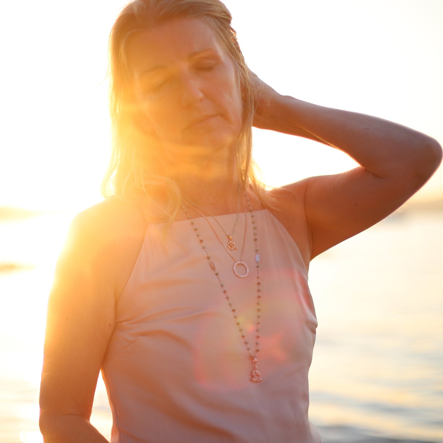 Im Gegenlicht: Die Frankfurter Reiki Therapeutin Corinna Marx trägt einen Lehrender-Buddha-Schmuckanhänger aus rosévergoldetem Sterling Silber an einer langen Jadekette
