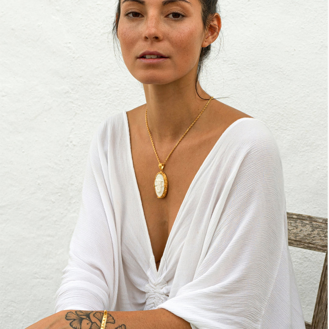 Die Yogalehrerin Steffi, in weißem Gewand, trägt einen hochwertig vergoldeten Ganesha Anhänger mit geschnitztem Einleger und reich verziertem Rahmen an einer kräftigen Halskette von ETERNAL BLISS - Spiritueller Schmuck