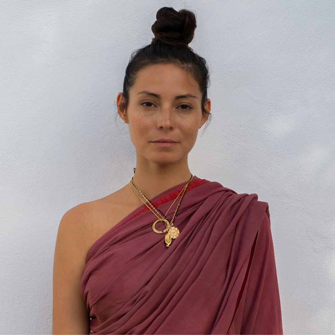 Yoga Teacher Steffi im roten Kleid kombiniert ihren Abhaya Mudra Anhänger zu verschiedenen vergoldeten spirituellen Ketten